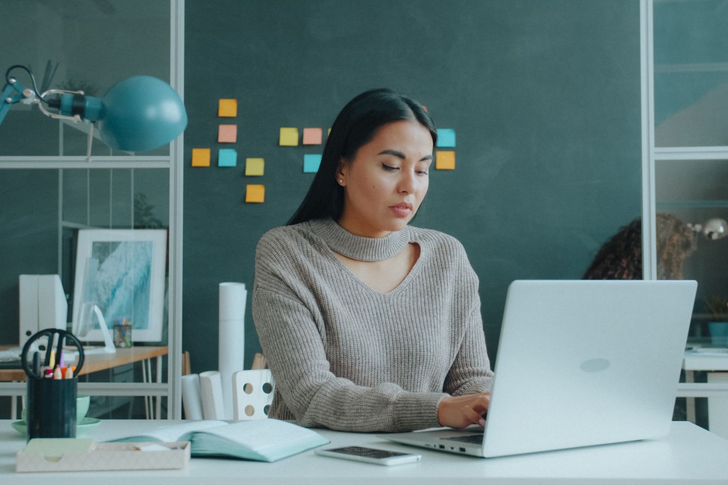 A professional starts her day at a laptop in a bright office.