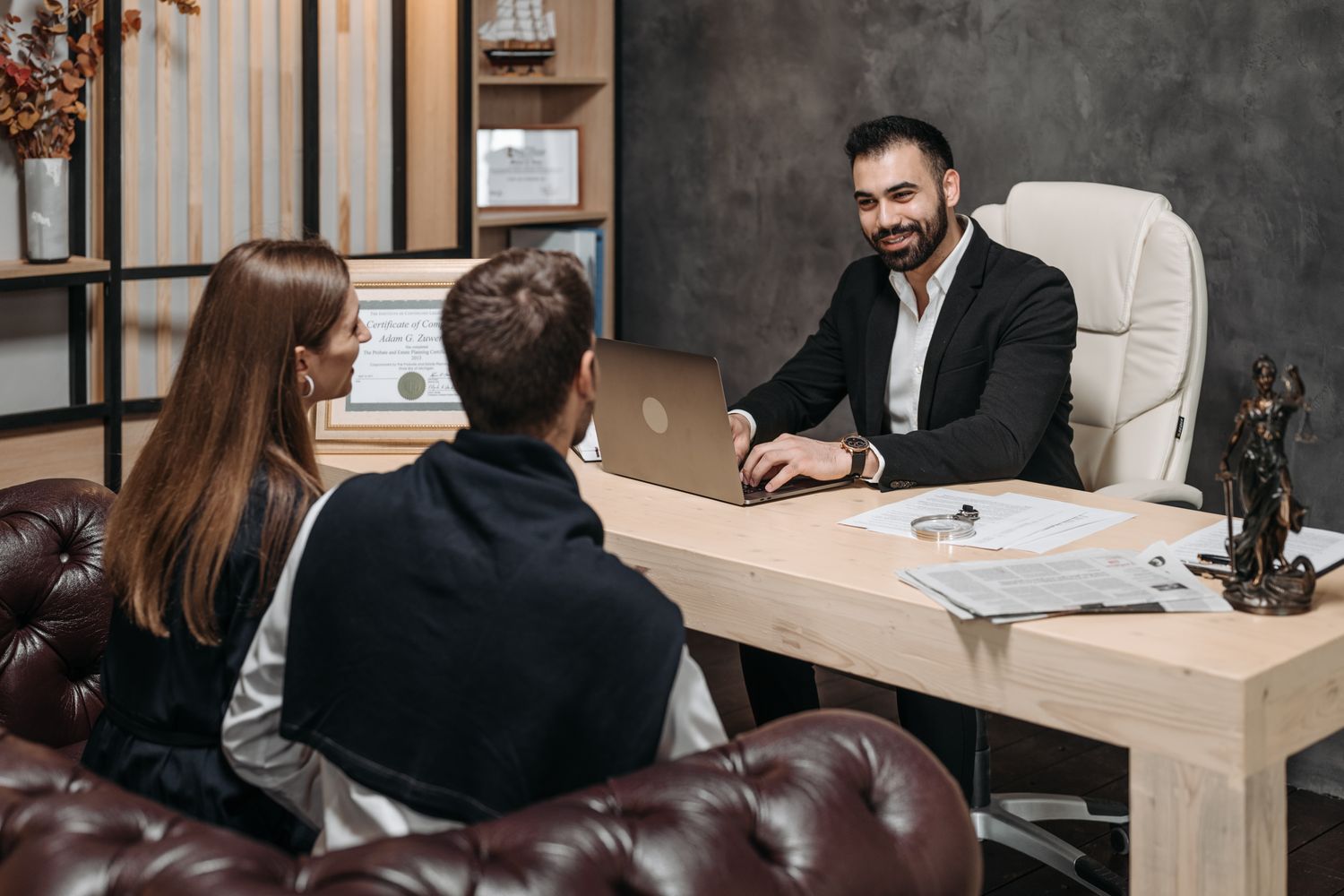 A couple meets their adviser across a desk in his office.