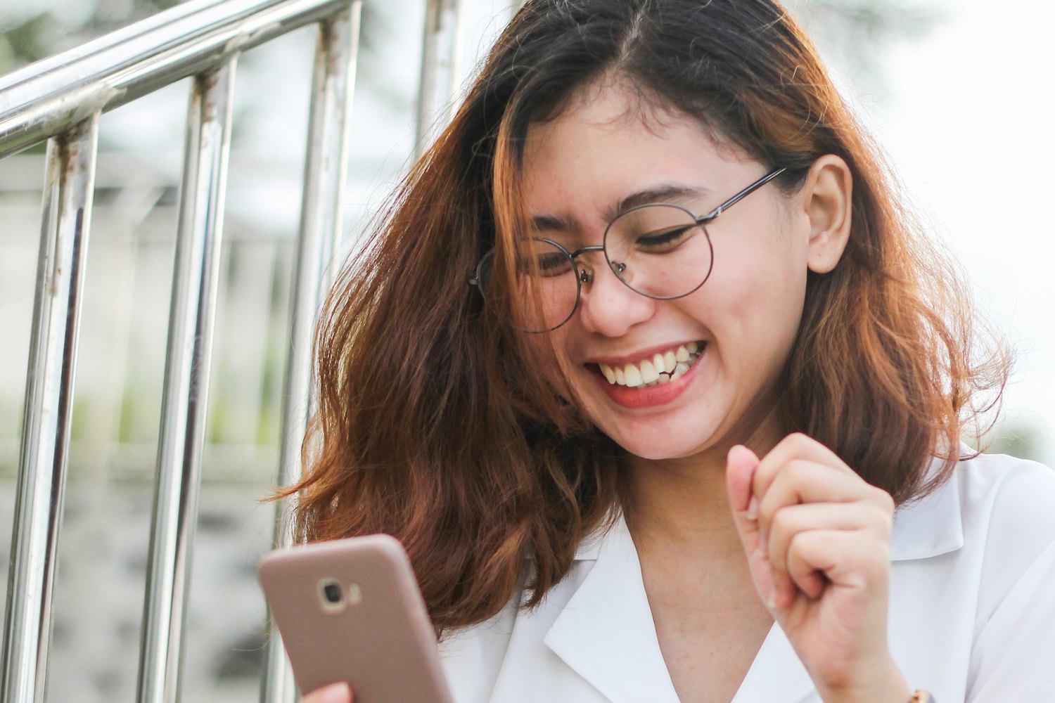 A young woman smiles at her phone.
