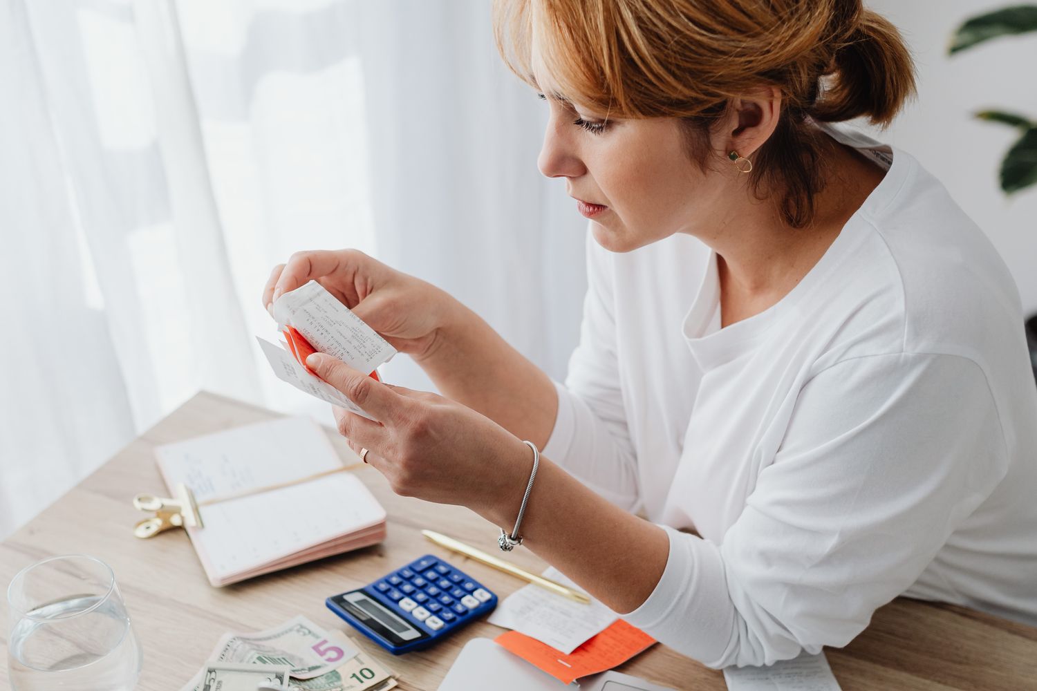 A professional checks a receipt at her desk, with a calculator beside her.